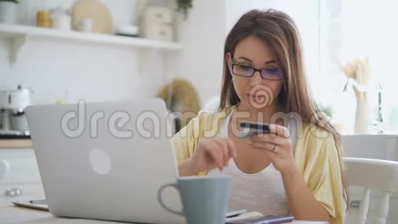 一位戴眼镜的漂亮女士她用自己崭新的笔记本电脑支付网上购物卡视频的预览图