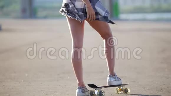 美丽的女孩单脚站在滑板上看着相机然后转身离开后视视频的预览图
