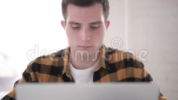 特写有头痛的年轻人在笔记本电脑上工作视频的预览图