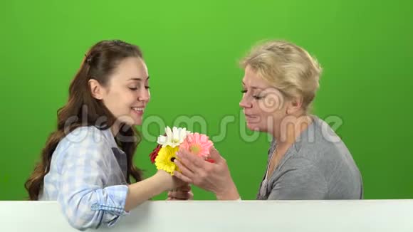 和她母亲在一起的女孩正在闻一束花绿色屏幕侧视图视频的预览图