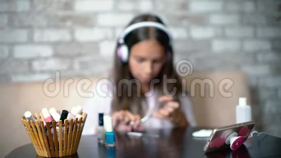 戴耳机穿家装的模糊女孩在电话里聊天修指甲视频的预览图