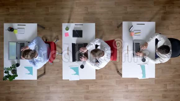 三个年轻的商人正在使用笔记本电脑同时离开工作场所工作观念办公室观念视频的预览图