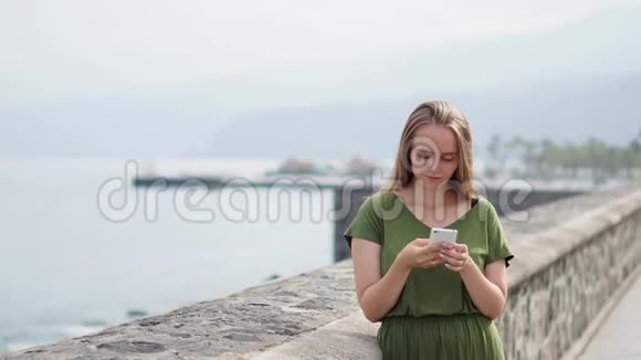 海普斯特女孩带着背包拿着智能手机小玩意在沙滩海岸线使用女性手提手机的旅行者视频的预览图