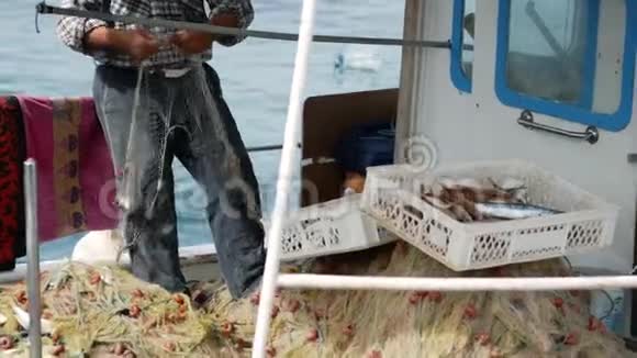 渔夫从渔网中捞出一条鱼土耳其博德鲁姆港的老年水手视频的预览图