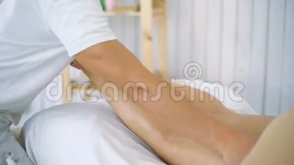 男按摩师在水疗中心特写的桌子上按摩美丽的年轻女子的腿视频的预览图