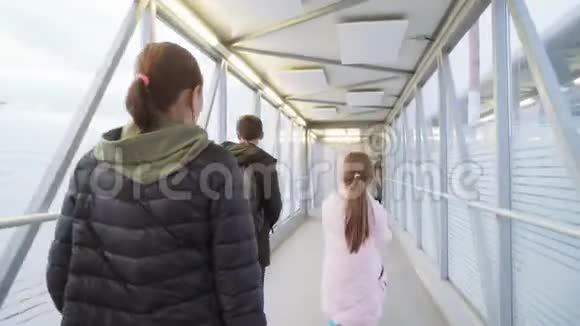 一个女人和她的女儿和儿子在一个伸缩坡道上到机场用手射击4k视频的预览图