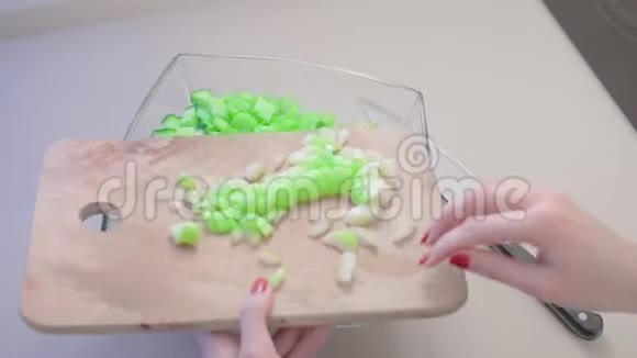 特写镜头动作缓慢一个未被认出的女人把切好的芹菜倒在木板上倒入一个大的玻璃沙拉碗里视频的预览图