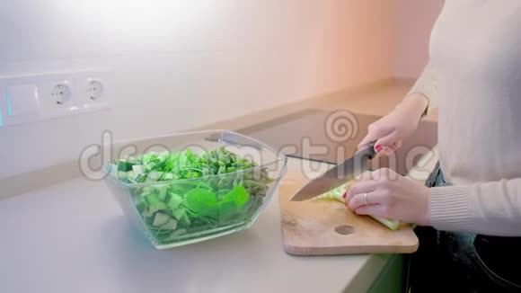 动作缓慢未被识别的女人用一把大菜刀把芹菜放在木板上切成玻璃色拉碗这就是视频的预览图