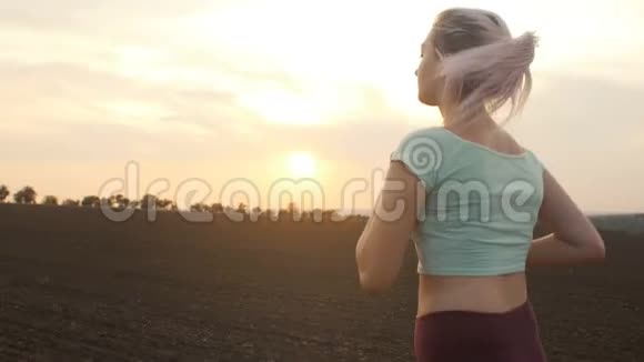 年轻女子在日落时分在野外慢跑女孩从事户外运动生活方式和健康的概念视频的预览图