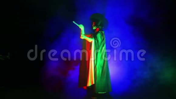 一个穿着黑色斗篷戴着帽子的年轻女巫手里拿着蜡烛手里拿着烟雾视频的预览图