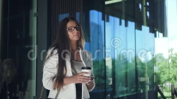 年轻漂亮的女商人正站在公司大楼附近喝咖啡休息视频的预览图