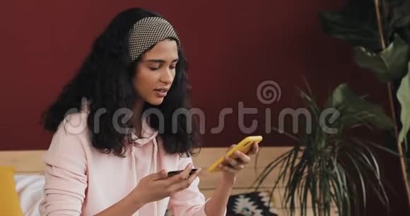 迷人的女孩拿着信用卡在床上使用智能手机快乐的年轻女子用手机网上购物视频的预览图