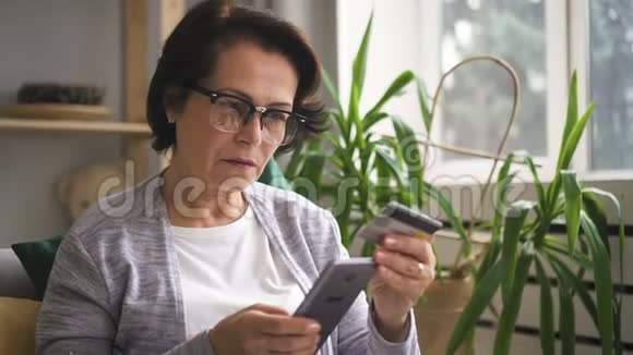 老年妇女在网上商店购物使用电话和银行卡视频的预览图
