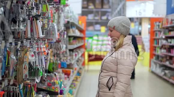 一个戴着帽子和羽绒服的女人穿过超市她看着货架上的货物选择视频的预览图