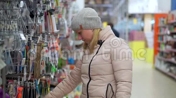 一个戴着帽子和羽绒服的女人穿过超市她看着货架上的货物选择视频的预览图
