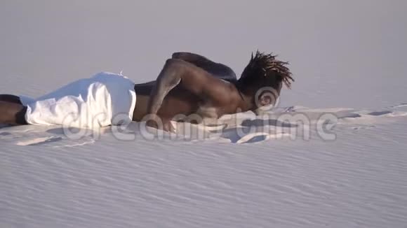 一个身穿紧身衣的黑人从沙滩上站起来看着镜头视频的预览图