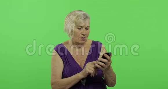 一位老年妇女在智能手机上工作老奶奶笑了铬键视频的预览图