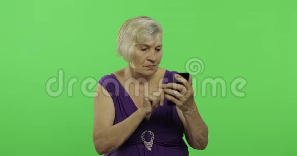 一位老年妇女在智能手机上工作老奶奶笑了铬键视频的预览图