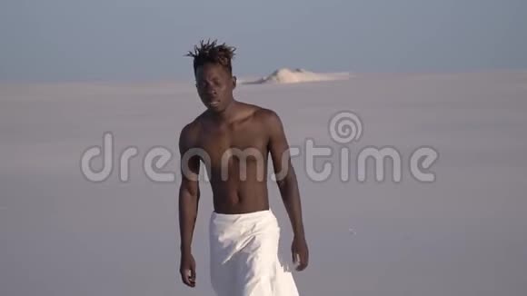 一个疲惫的奴隶穿着白色的紧身衣在沙漠中游荡视频的预览图