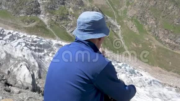 一个人坐在山上从高处看冰川视频的预览图