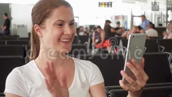 在机场候机室等待航班起飞时通过智能手机上的信使应用程序与女士交谈视频的预览图