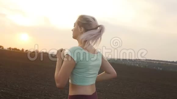 年轻女子在日落时分在野外慢跑女孩从事户外运动生活方式和健康的概念视频的预览图