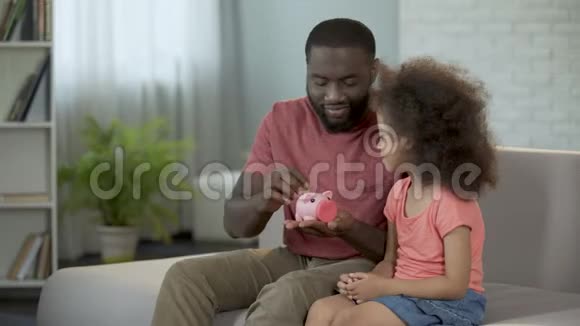 有爱心的父亲教孩子省钱把硬币放进储蓄罐视频的预览图