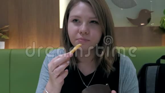 在快餐店吃炸薯条的漂亮女孩的特写镜头不健康的食物视频的预览图
