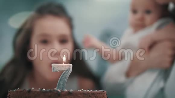 在家庭聚会上女孩在生日蛋糕上吹蜡烛孩子生日快乐视频的预览图