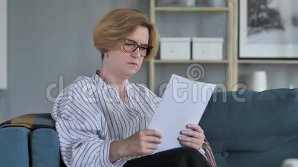 佩尼斯夫老年女性阅读协议坐沙发视频的预览图
