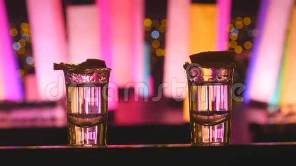 一对夫妇在酒吧柜台上喝两杯带有石灰的龙舌兰酒颜色变化的LED管灯视频的预览图