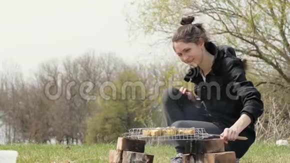 在野外野餐时一位年轻女子在火上烧肉视频的预览图