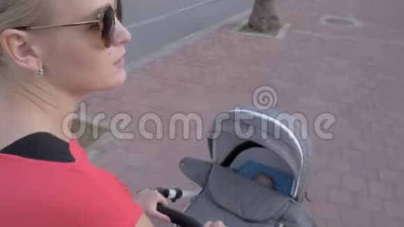 年轻的妈妈带着婴儿在婴儿车里睡觉视频的预览图