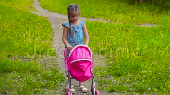 带着婴儿车和娃娃在公园散步的小女孩视频的预览图