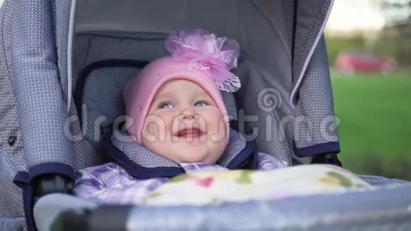 可爱的小女孩坐在婴儿车里smiling在街上大自然视频的预览图