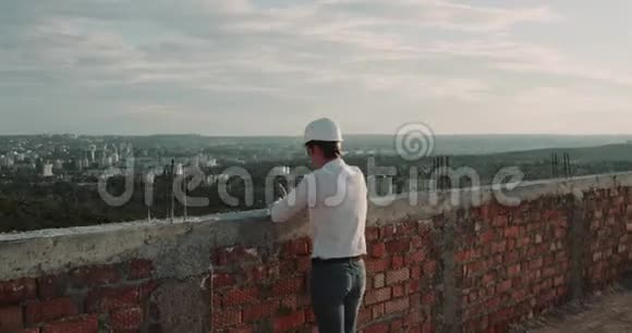 一个建筑工地上的男人从屋顶上看着令人惊叹的城市景色视频的预览图