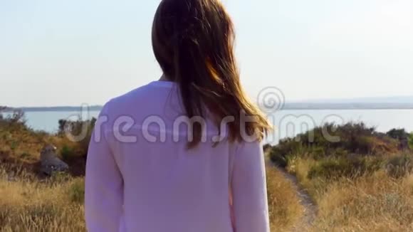 女人在湖边的草地上散步举起手臂女性旅行者慢动作伸出双手视频的预览图