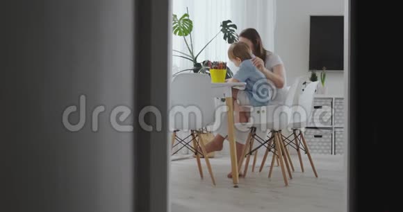 一位年轻的母亲带着两个孩子坐在白色的桌子旁慢慢地在纸上画着彩色铅笔视频的预览图