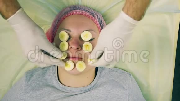 化妆师的男人的手在女人的脸上放了一个香蕉上的面具视频的预览图