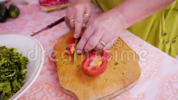 一个女人在切割板上切西红柿准备蔬菜沙拉的过程视频的预览图