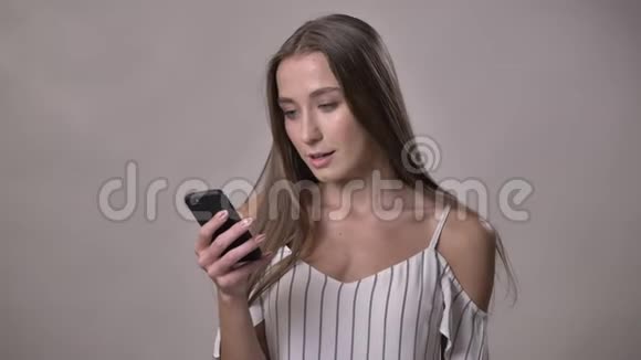 年轻兴奋的女孩正在展示绿色的智能手机屏幕哇看着相机微笑交流理念灰色视频的预览图
