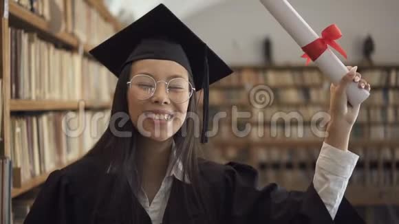 穿着学术礼服的女生微笑着站在图书馆里视频的预览图