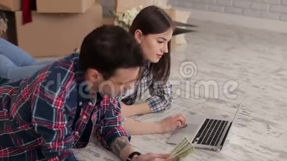 新婚夫妇在一间新公寓里大箱子里放着一台笔记本电脑视频的预览图