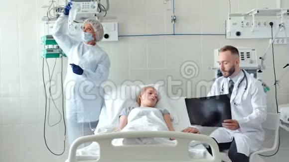 男医生在病床上和女病人交谈护士在医院病房为生病的年轻妇女准备滴管视频的预览图