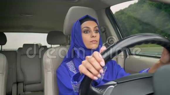 年轻迷人的穆斯林妇女戴着头巾开车上路视频的预览图
