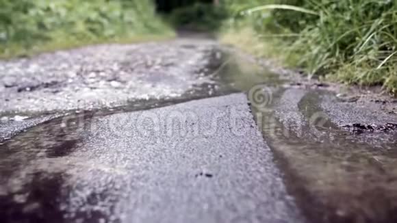 草地背景下雨中泥泞小路的特写库存录像在泥泞中拍摄雨滴的宏观拍摄视频的预览图