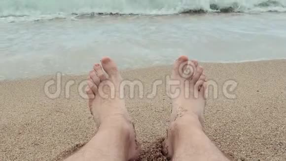 第一人称的人的脚在沙滩上放松背景是一片波涛汹涌的大海视频的预览图