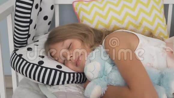 可爱的小女孩和泰迪熊睡在床上视频的预览图