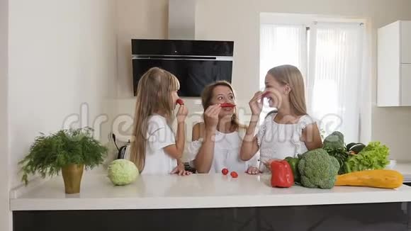 两个姐妹和他们的母亲正在厨房的家里玩辣椒女孩们用红色做胡子视频的预览图