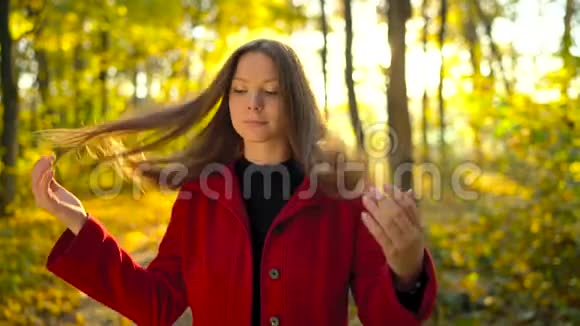 秋天森林里一个身穿红色外套背景是一片黄色枫叶的美丽沉思少女的画像视频的预览图